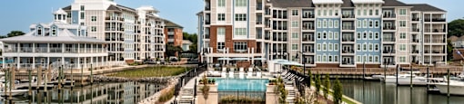 A large building with a pool in front of it at The Port at East Beach Apartments and Marina in Norfolk, VA, 23518