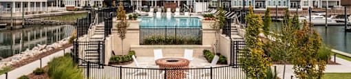 A view of a pool and a building with a fence around it at The Port at East Beach Apartments and Marina in Norfolk, 23518