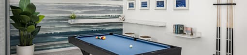 A pool table in a room with a painting on the wall at The Port at East Beach Apartments and Marina in Virginia, 23518