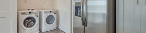 a laundry room with a washer and dryer and a stainless steel refrigerator at The Port at East Beach Apartments and Marina, Norkfolk, VA