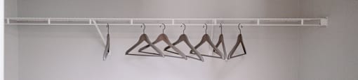 A white closet with clothes hangers.