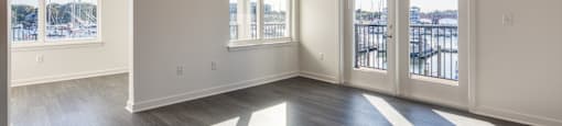an empty living room with windows and a ceiling fan at The Port at East Beach Apartments and Marina, Norkfolk, VA, 23518