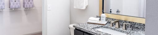 A bathroom with a toilet, sink, and mirror.