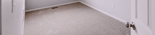 A room with a carpeted floor and a window with blinds.