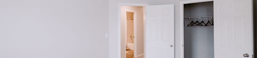 A room with a white door and a grey carpet.