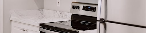 A white kitchen with a refrigerator, oven, and microwave.