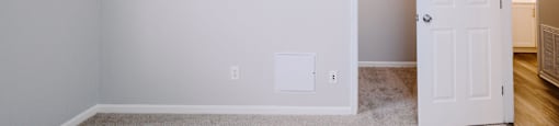 A room with a white door and a carpeted floor.