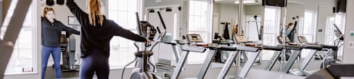 A woman is working out in a gym with a mirrored wall.