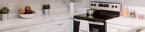 A kitchen with white cabinets and a black stove top oven.
