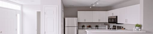 A white kitchen with a refrigerator and cabinets.