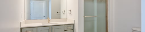 a bathroom with a sink and a mirror and a shower at The Port at East Beach Apartments and Marina, Virginia