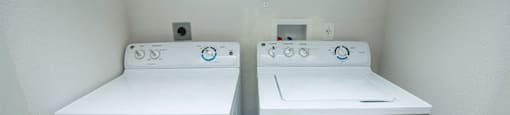 Two white front loading washing machines in a small laundry room.
