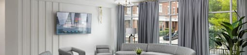 A modern living room with a grey sofa set and a television on the wall at The Port at East Beach Apartments and Marina in Norfolk, VA