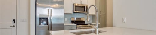 a kitchen with stainless steel appliances and white cabinets at The Port at East Beach Apartments and Marina, Virginia