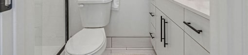 a white bathroom with a toilet, a sink, and a shower
