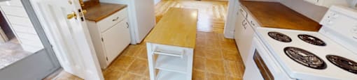 A kitchen with white appliances and wooden floors.