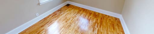 A room with wooden floors and two windows.