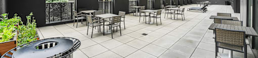 A patio with tables and chairs is surrounded by buildings.