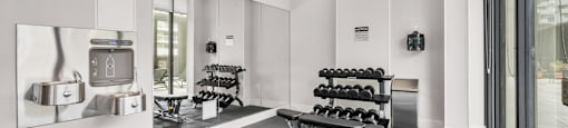 A gym with a mirror, weights, and exercise equipment.