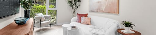 A living room with a white couch and a painting on the wall.