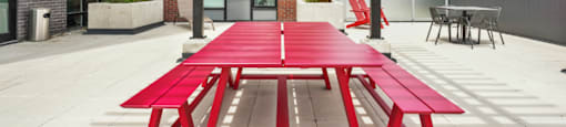 A red picnic table is in the middle of a patio.