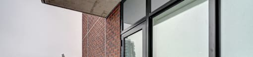 A balcony with glass doors and a brick wall.
