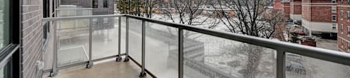 A balcony with a glass railing and a view of a snowy landscape.