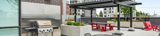 A patio with a grill, chairs, and a table.