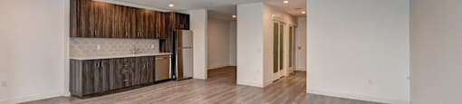 A spacious room with wooden flooring and a white wall.