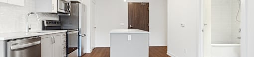 A kitchen with white cabinets and a wooden floor.
