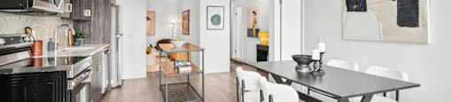 A modern kitchen with a black countertop and white chairs.