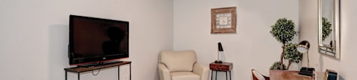 A living room with a television, chair, and table.