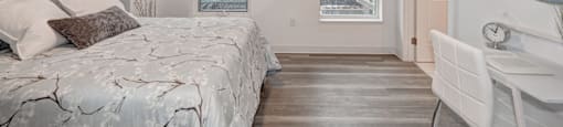 A bedroom with a bed, chair, and mirror.