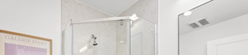 A bathroom with a white toilet, a walk-in shower, and a white sink.