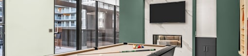 A pool table is in the middle of a room with a television and a fireplace.