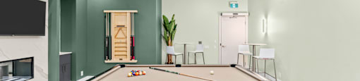 A pool table is in the middle of a room with green walls.