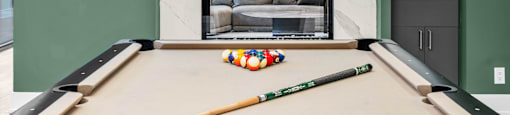 A pool table with a green cue stick and a ball on it.