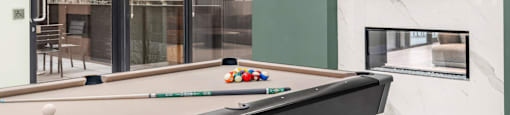 A pool table with a green wall and a television mounted on it.