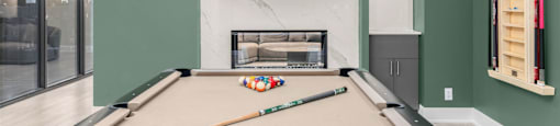 A pool table with a white ball on it and a TV mounted on the wall.