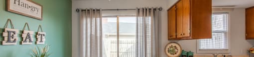 Model unit dining area with a table and chairs next to a kitchen with a sliding glass door