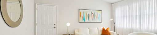 A living room with a white couch, a coffee table, and a painting on the wall.
