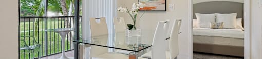 A dining room with a glass table and chairs and a painting on the wall.