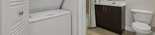 A white washing machine is in a bathroom with a toilet and sink.