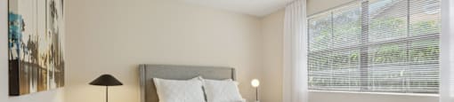 A bedroom with a large bed and a nightstand with a lamp.