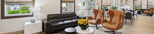 A modern living room with a brown leather couch and a coffee table with a vase of flowers on it.