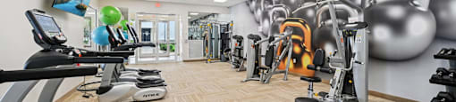 A gym with a variety of equipment including treadmills, weights, and exercise machines.