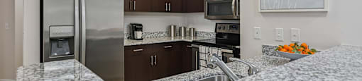 A kitchen with a granite counter top and stainless steel appliances.