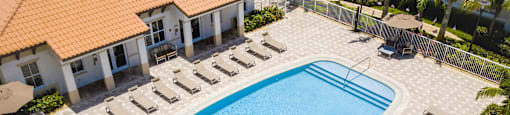 A large swimming pool surrounded by sun loungers and umbrellas.