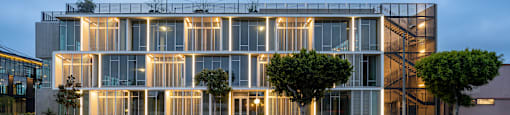 A modern building with a glass facade and a tree in front of it.