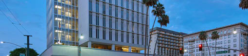 A modern building with a glass facade and a red logo on the top left corner.